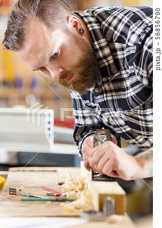 Carpenter work with planer on wood plank in workshop Carpenter work with planer on wood plank in workshop 56856790