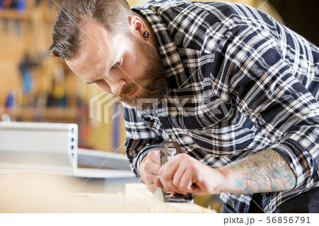 Carpenter work with plane on wood plank in workshop 56856791