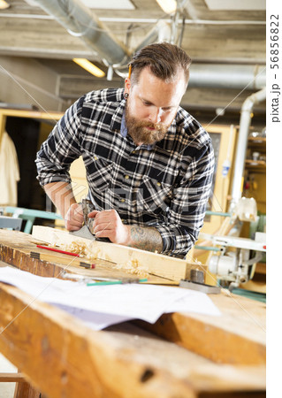 Carpenter work with plane on wood plank in workshop Carpenter work with plane on wood plank in workshop 56856822