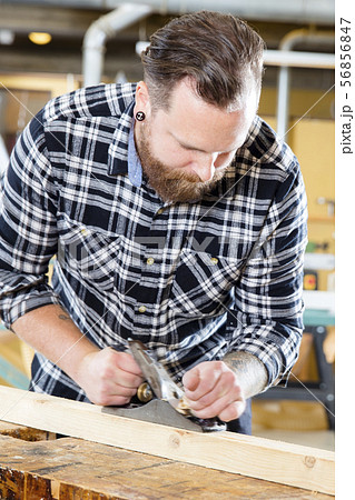 Carpenter work with planer on wood plank in workshop Carpenter work with planer on wood plank in workshop 56856847