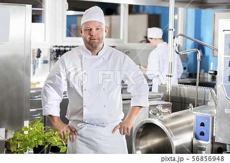 Portrait of confident and smiling chef making food in large kitchen Portrait of confident and smiling chef making food in large kitchen 56856948