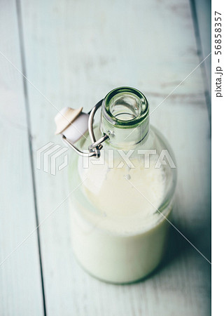 Milk in glass bottle on wooden surface Milk in glass bottle on wooden surface 56858357