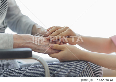シニア女性の手を握る女性の手の写真素材