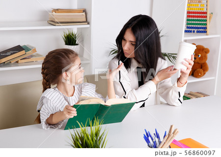 Pretty mother with cute daughter sitting with book in the room at home. Pretty mother with cute daughter sitting with book in the room at home. 56860097