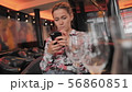 Young female French uses social networks to communicate with a mobile phone. Sits in a restaurant on 56860851