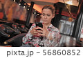 Young female French uses social networks to communicate with a mobile phone. Sits in a restaurant 56860852