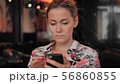 Caucasian young female uses smartphone while sitting in a restaurant. Slow Motion 56860855