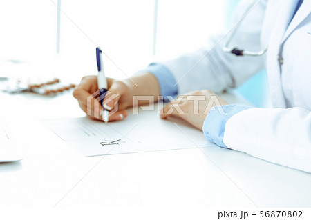 Female doctor filling up prescription form while sitting at the desk in hospital closeup. Healthcare Female doctor filling up prescription form while sitting at the desk in hospital closeup. Healthcare 56870802