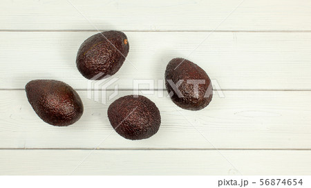 Four ripe brown avocados on white boards desk. 56874654