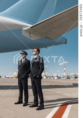 Adult men in uniform posing for camera in airport Adult men in uniform posing for camera in airport 56875460