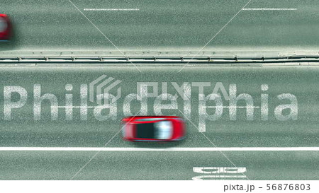 Aerial down view of the motorway with cars revealing Philadelphia caption. Car travel to the United 56876803