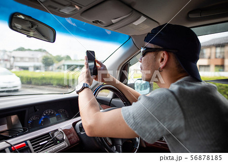 スマートフォン見ながら自動車を運転する男性 56878185