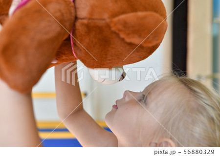 Girl playing with a toy bear in a children room Girl playing with a toy bear in a children room 56880329
