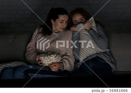 Teenage girls watching horror movie with popcorn Teenage girls watching horror movie with popcorn 56881666