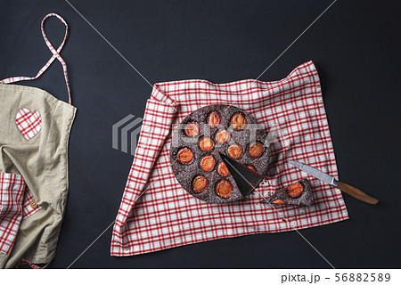 Plums cake on a kitchen table with apron and towel 56882589