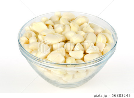 Peeled garlic cloves in glass bowl, front view 56883242