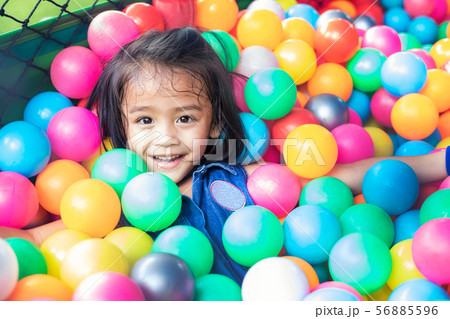 Happy little girl sitting in colourful balls. 56885596