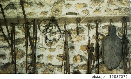 Forged items, tools of ancient times hang on the wall of the barn Forged items, tools of ancient times hang on the wall of the barn 56887075