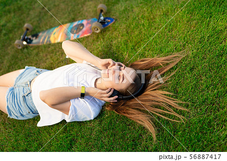 Young girl enjoy lay in green lawn and listening 56887417