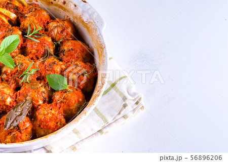 Homemade meatballs with tomato sauce in a white dish baked in the oven with herbs on marble white Homemade meatballs with tomato sauce in a white dish baked in the oven with herbs on marble white 56896206