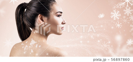 Young woman over beige background with snowflakes. 56897860
