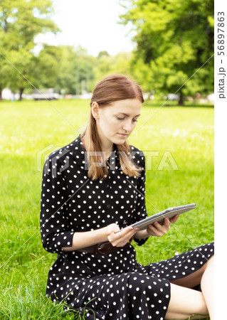 Blogger talking on line in a video conference with a laptop sitting on a bench in the street 56897863