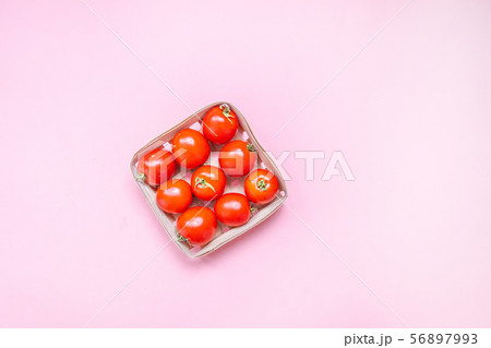 Red cherry tomatoes in a woven basket on a pink background 56897993