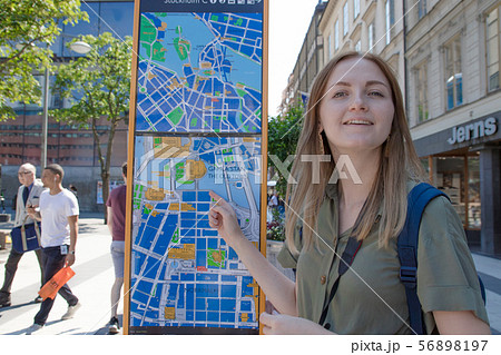 Young blonde girl orientating herself on the public map. Young blonde girl orientating herself on the public map. 56898197
