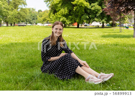 Beautiful young woman sits on the grass. Fresh natural summer concert. 56899913