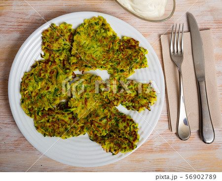 Zucchini pancakes with white sauce on withe plate Zucchini pancakes with white sauce on withe plate 56902789