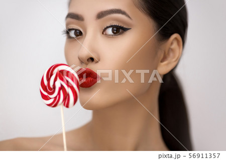 Fashion Portrait of Asian Woman with Lollipop in Studio 56911357