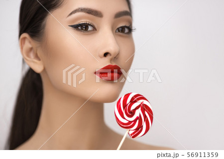 Fashion Portrait of Asian Woman with Lollipop in Studio 56911359
