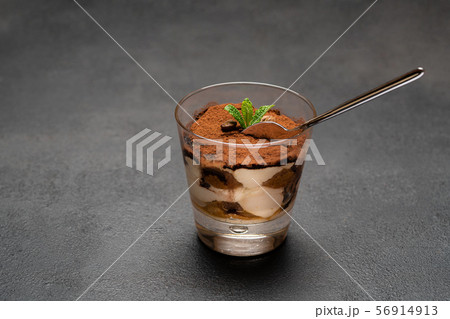 Portion of Classic tiramisu dessert in a glass cup on dark concrete background Portion of Classic tiramisu dessert in a glass cup on dark concrete background 56914913