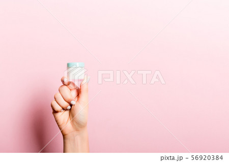 Female hand holding cream bottle of lotion 56920384