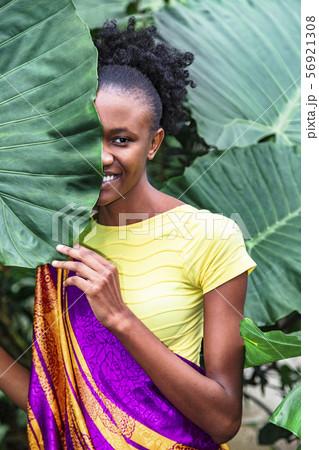 African girl hid behind palm leaf and smiles African girl hid behind palm leaf and smiles 56921308