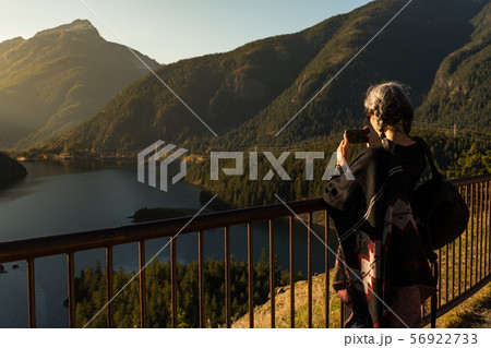 A young woman with white hair takes photographs with her smartphone of Diablo Lake, in North 56922733