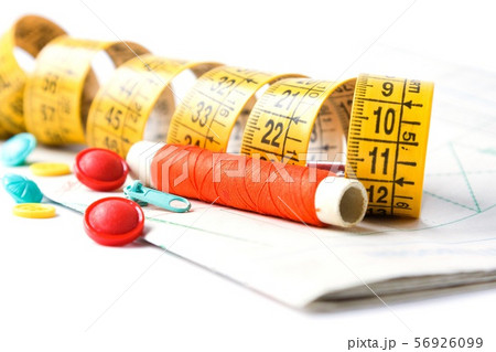 Sewing supplies on white sewing thread, scissors, pattern, centimeter, buttons Sewing supplies on white sewing thread, scissors, pattern, centimeter, buttons 56926099