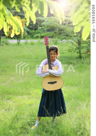Asian school girl playing the guitar on the lawn , 56938099