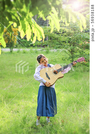 Asian school girl playing the guitar on the lawn , 56938188