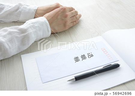 退職願と悩む人物の手元 56942696