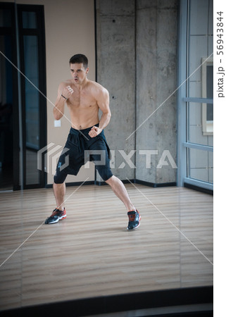 An athletic man boxer in black shorts training in the studio 56943844