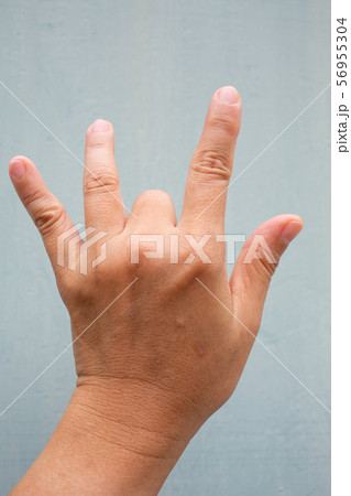 Trigger Finger lock on middle finger of woman's back left hand, Suffering from pain, On Blue-grey colour background, Close up & Macro shot, Office syndrome, Health care concept Trigger Finger lock on middle finger of woman's back left hand, Suffering from pain, On Blue-grey colour background, Close up & Macro shot, Office syndrome, Health care concept 56955304