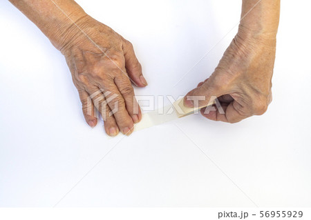 Senior woman's hands holding and using sticky tape isolated on white background 56955929