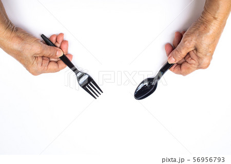 Senior woman's hands holding black plastic spoon and fork isolated on white background 56956793