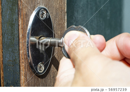 Woman's left hand use a key for lock or unlock wooden door, Close up & Macro shot, Selective focus, Security concept 56957239