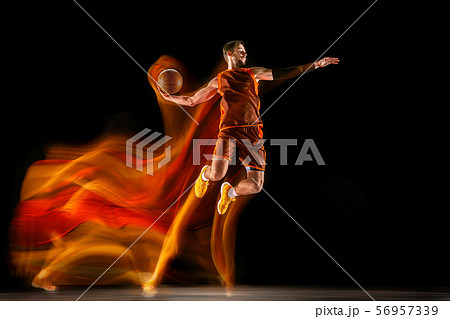 Young caucasian basketball player against dark background in mixed light Young caucasian basketball player against dark background in mixed light 56957339