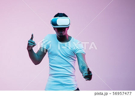 Young african-american man's using VR-glasses in neon light Young african-american man's using VR-glasses in neon light 56957477