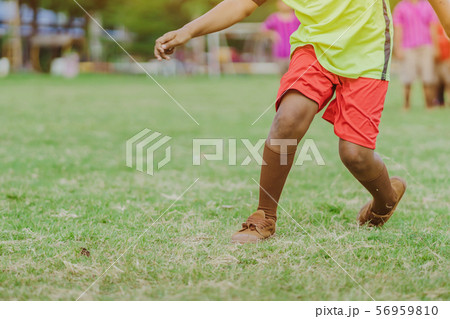 Asian boys practice kicking the ball to score goals in the public football field. Asian boys practice kicking the ball to score goals in the public football field. 56959810