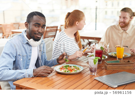 Man with friends eating in cafe Man with friends eating in cafe 56961156