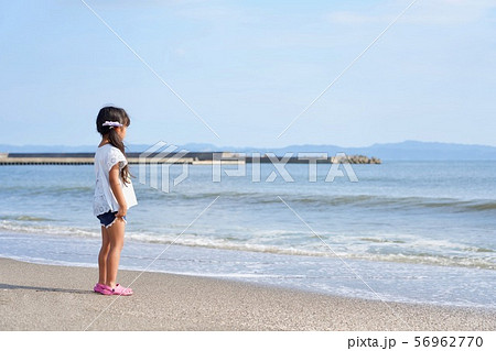 浜辺から海を見つめる女の子の写真素材